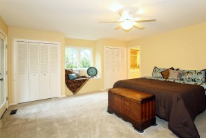 Huge master bedroom with entrance to outdoor deck, pool beyond window seat
