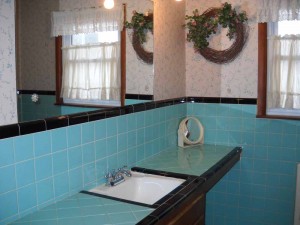Hall bath in a beautiful and original turquoise blue tile, reglazed tub & spacious cabinetry!