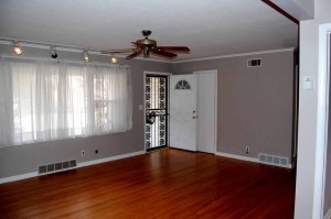 Living room with crown molding & baseboards; wrought iron storm door; hall closet