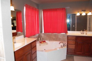 Whirlpool with jets and tile border and separate vanities with sinks on either side